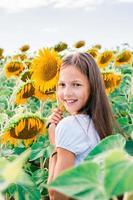 menina alegre abraça um girassol em um campo ao sol. turismo local e liberdade foto