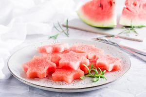 pedaços de melancia fresca em forma de estrelas em um prato na mesa. refresco de verão. foto