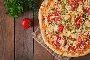 pizza com salame, tomate e cogumelos foto