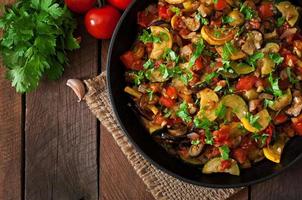 ratatouille de legumes na frigideira em uma mesa de madeira foto