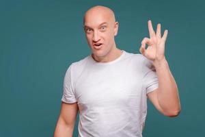 retrato de um homem alegre mostrando gesto bem isolado no fundo azul foto