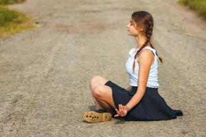 jovem sentada na estrada e meditando, relaxe foto