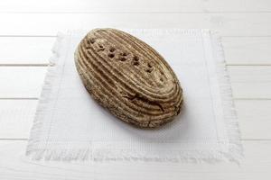 pão de centeio redondo tradicional em pano branco fabrick. pão em fundo de madeira foto