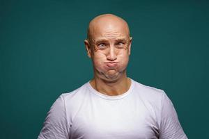 retrato de um homem careca estufou as bochechas em um fundo azul foto