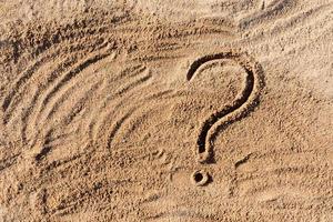 pontos de interrogação escritos na areia da praia de perto, com espaço de cópia foto
