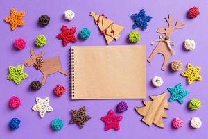 vista superior do notebook. decorações de ano novo em fundo roxo. estrelas e bolas festivas. feliz natal conceito foto