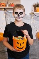 a criança tira o doce do balde para o halloween foto