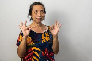 retrato de menina mais velha asiática mostra a mão ok no espaço de cópia de fundo. foto