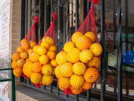 três redes de embalagem com laranjas penduradas em barras de aço de janela para venda foto