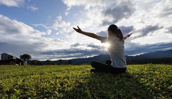 mulher orando por graças a deus orando com as mãos juntas para pensar em um deus amoroso, louvamos a deus com reflexo de luz na natureza verde. foto