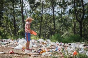 um menino pobre coletando resíduos de lixo de um aterro sanitário. conceito de subsistência de crianças pobres. Trabalho infantil. trabalho infantil, tráfico humano, conceito de pobreza foto