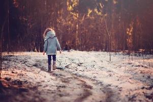menina criança andando na estrada na floresta de inverno
