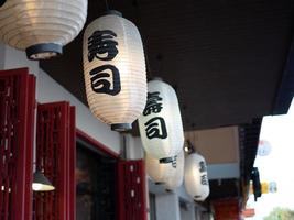 lanterna japonesa pendurada na frente do restaurante japonês, texto japonês na lanterna é comida japonesa de sushi. foto