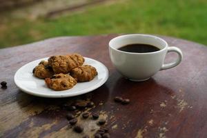 xícara de café preto com biscoitos no chão de madeira, café preto de manhã para beber com biscoitos. foto