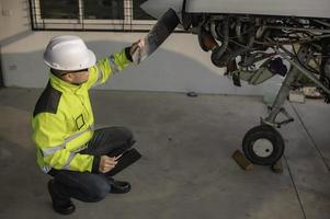 técnico consertando o motor do avião, engenharia aeroespacial masculina verificando motores de aeronaves, manutenção mecânica asiática inspeciona motor de avião foto