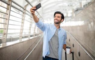 o homem usando selfies de smartphone sozinho enquanto espera seu amigo no aeroporto. foto