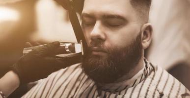 homem barbudo cortando a barba no cabeleireiro foto