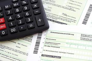 declaração de retorno de imposto de renda anual alemão e calculadora encontra-se na mesa do contador close-up. o conceito de período de pagamento de impostos na alemanha foto