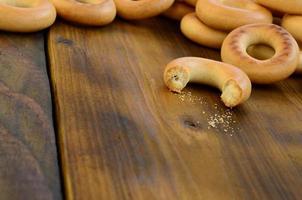 muitos bagels amarelos frescos estão na superfície da velha madeira escura. um tipo popular de produtos de farinha. uma das guloseimas tradicionais russas para o chá foto