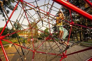 as crianças brincam na escalada de poliedro de corda no playground ao ar livre. foto