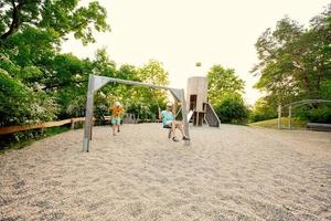 dois irmãos balançam no brinquedo do parque infantil situado no parque público. foto