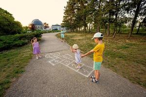 crianças brincando de amarelinha no parque. crianças atividades ao ar livre. foto