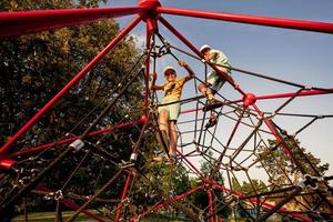 irmãos jogam na escalada de poliedro de corda no playground ao ar livre. foto