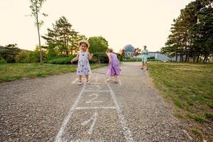 duas irmãs jogando amarelinha no parque. jogo infantil, atividades ao ar livre para crianças. foto