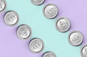 muitas latas de cerveja metálica no fundo de textura de papel de cores violeta e azul pastel de moda em conceito mínimo foto