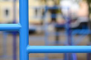 tubos de metal azul e barras transversais contra um campo de esportes de rua para treinamento de atletismo. equipamento de ginástica esportiva ao ar livre. foto macro com foco seletivo e fundo extremamente desfocado