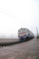 o trem suburbano ucraniano corre ao longo da ferrovia em uma manhã nublada. foto olho de peixe com distorção aumentada