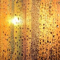 a textura do vidro embaçado com muitas gotas e gotas de condensação contra a luz do sol ao amanhecer. imagem de fundo foto