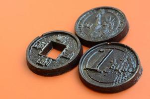 três produtos de chocolate na forma de moedas de euro, eua e japão encontram-se em um fundo de plástico laranja. um modelo de moedas de dinheiro em forma comestível foto