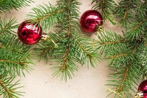 galhos de árvores do abeto decorados com bolas vermelhas de natal como borda em um quadro de fundo de férias rústico com espaço de cópia foto