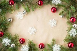 fronteira festiva de natal com bolas vermelhas e prateadas em ramos de abeto e flocos de neve em fundo bege rústico foto