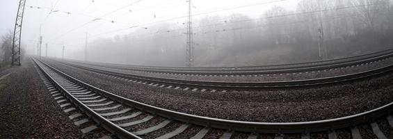 a ferrovia em uma manhã nublada. muitos trilhos e dormentes vão para o horizonte enevoado. foto olho de peixe com distorção aumentada