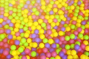 muitas bolas de plástico coloridas em uma piscina infantil em um playground. padrão de close-up foto