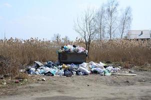 a lata de lixo é embalada com lixo e resíduos. remoção prematura de lixo em áreas povoadas foto