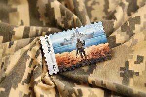 ternopil, ucrânia - 2 de setembro de 2022 famoso carimbo postal ucraniano com navio de guerra russo e soldado ucraniano como lembrança de madeira no uniforme de camuflagem do exército foto