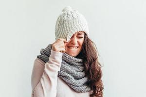 menina rindo usando chapéu de roupas quentes e cachecol isolado no fundo branco foto