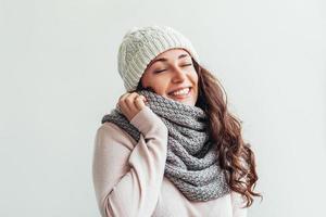 menina rindo usando chapéu de roupas quentes e cachecol isolado no fundo branco foto