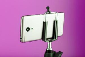 smartphone em um tripé como uma câmera de foto-vídeo em um fundo rosa. gravar vídeos e fotos para o seu blog.
