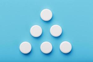 comprimidos medicinais redondos na forma de um triângulo sobre um fundo azul, isolado. foto