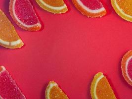 geléia de frutas em forma de fatias de laranja e toranja em um background.sweets vermelho em cima da mesa. foto