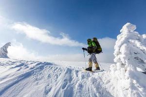 homem mochileiro caminhando nas montanhas de inverno em dia ensolarado