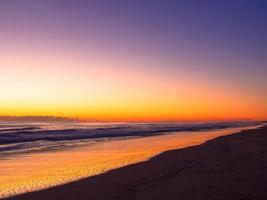 cor laranja do nascer do sol na longa linha de praia foto