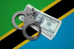 bandeira da tanzânia com algemas e um pacote de dólares. corrupção monetária no país. crimes financeiros foto