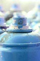 muitas latas de aerossol sujas e usadas de tinta azul brilhante. fotografia macro com profundidade de campo rasa. foco seletivo no bico de pulverização foto