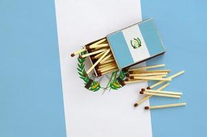 a bandeira da guatemala é mostrada em uma caixa de fósforos aberta, da qual caem vários fósforos e fica em uma grande bandeira foto