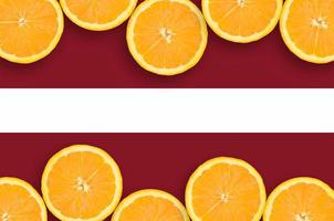 bandeira da letônia em moldura horizontal de fatias de frutas cítricas foto